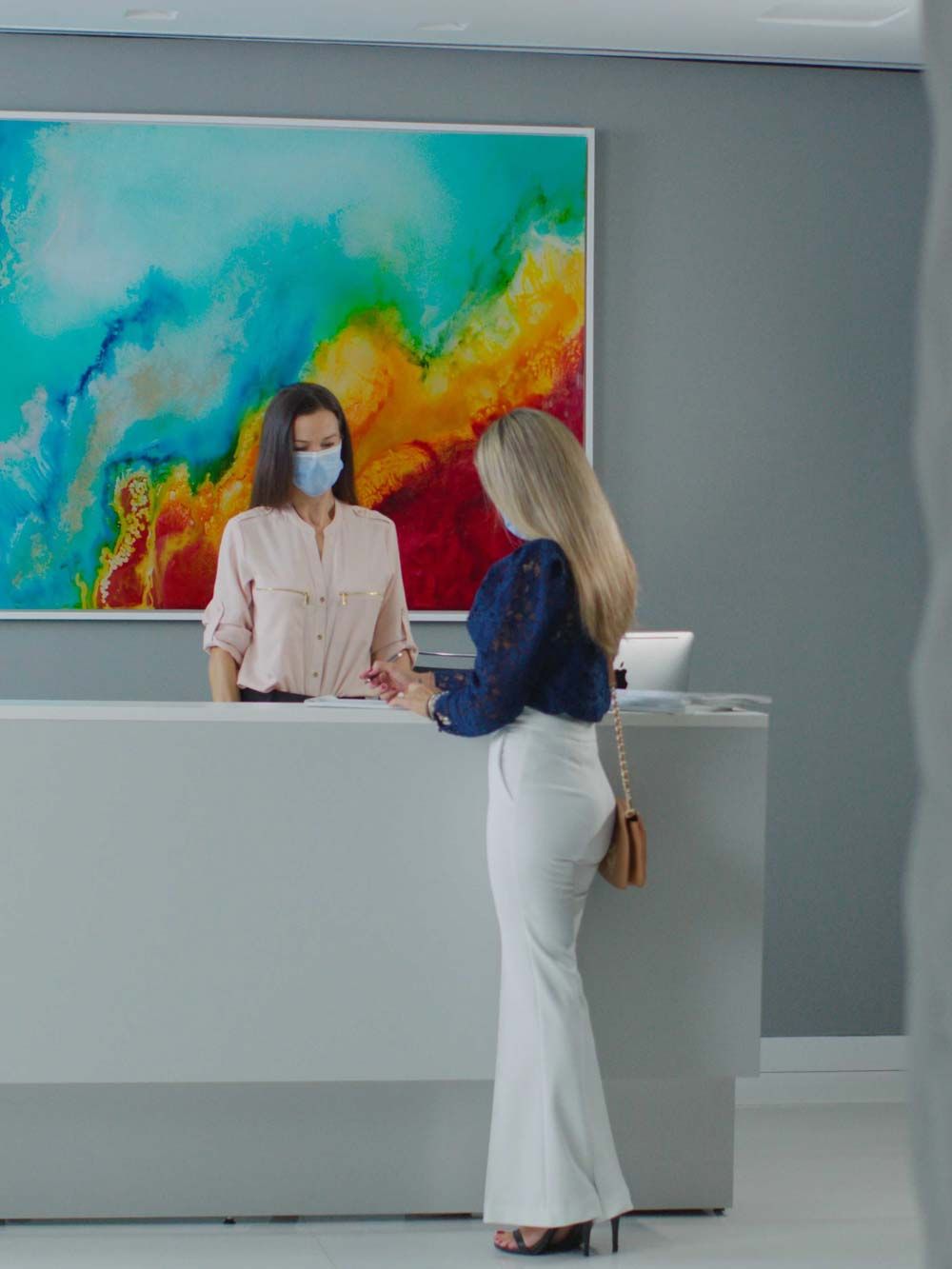 Woman at front desk, colorful artwork on wall